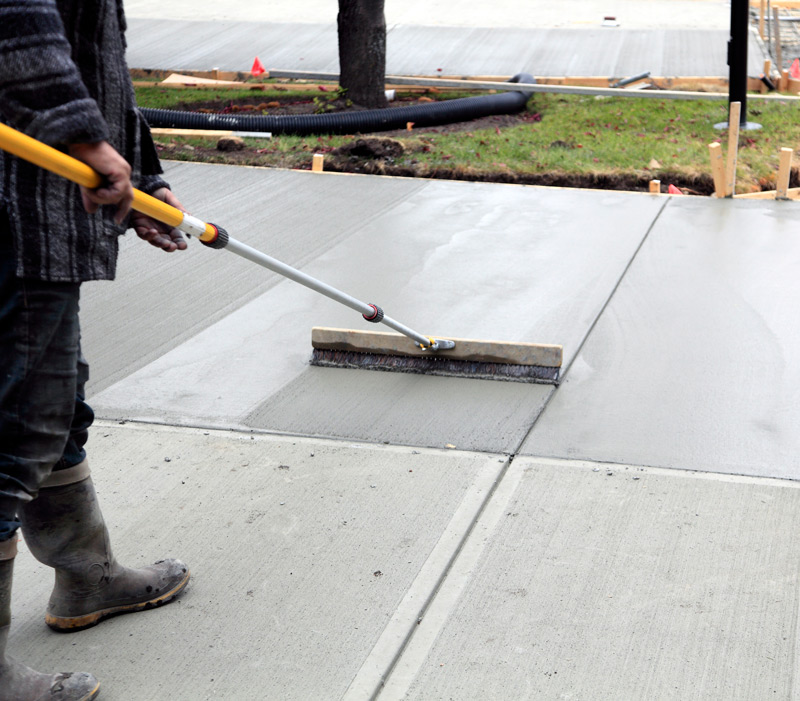 Worker adding texture to a new concrete slab